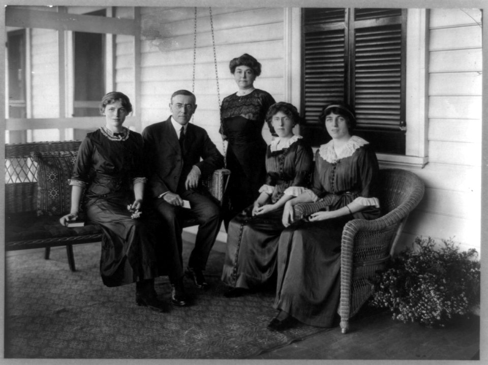 Woodrow Wilson, seated posed on swing on porch, facing front, with his wife and three daughters LCCN89709244