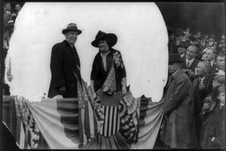 Woodrow Wilson, half length, standing, facing right; and his wife (Edith Bolling Galt), on flag-draped platform in front of crowd LCCN2006690218