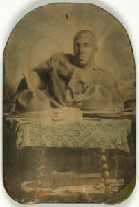 World War I soldier, half-length portrait, seated, facing front, with two hats on table LCCN2002719501