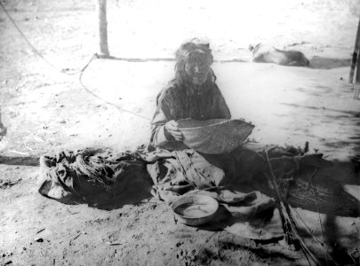Yokut Indian woman sifting corn meal in a reed basket, Tule River Reservation near Porterville, California, ca.1900 (CHS-3800)