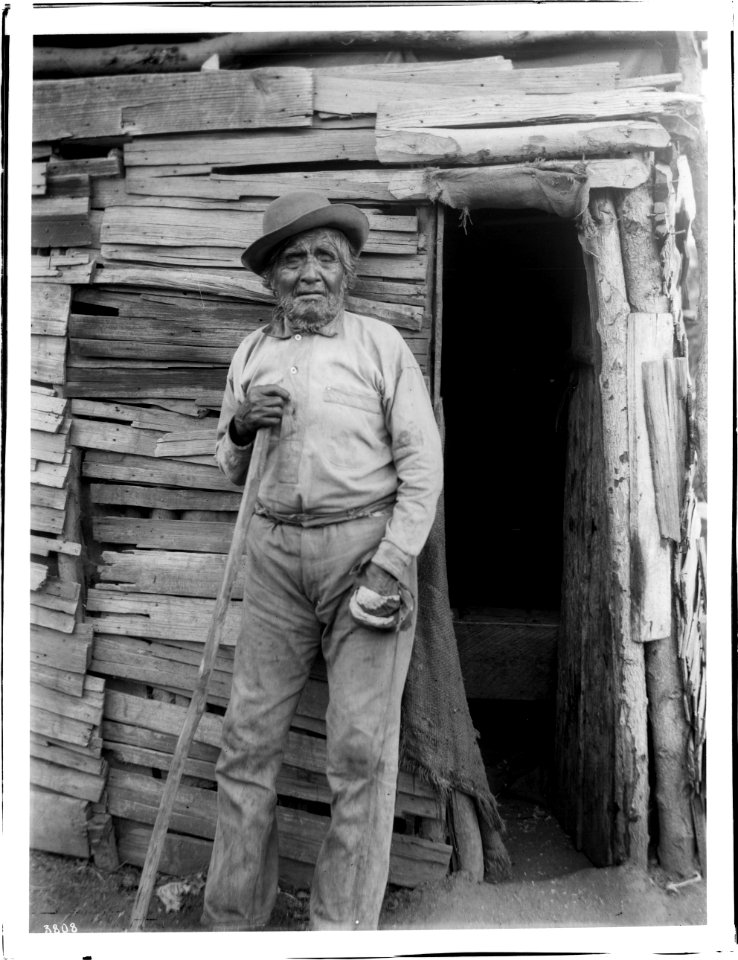 Yokut Indian man standing beside a shake house, Tule River Reservation near Porterville, California, ca.1900 (CHS-3808)