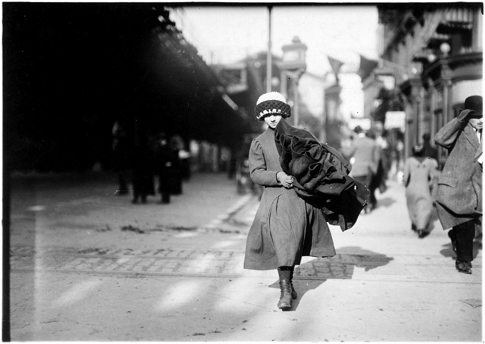 Young girl carrying bundle of coats home to be finished. New York City. - NARA - 523520