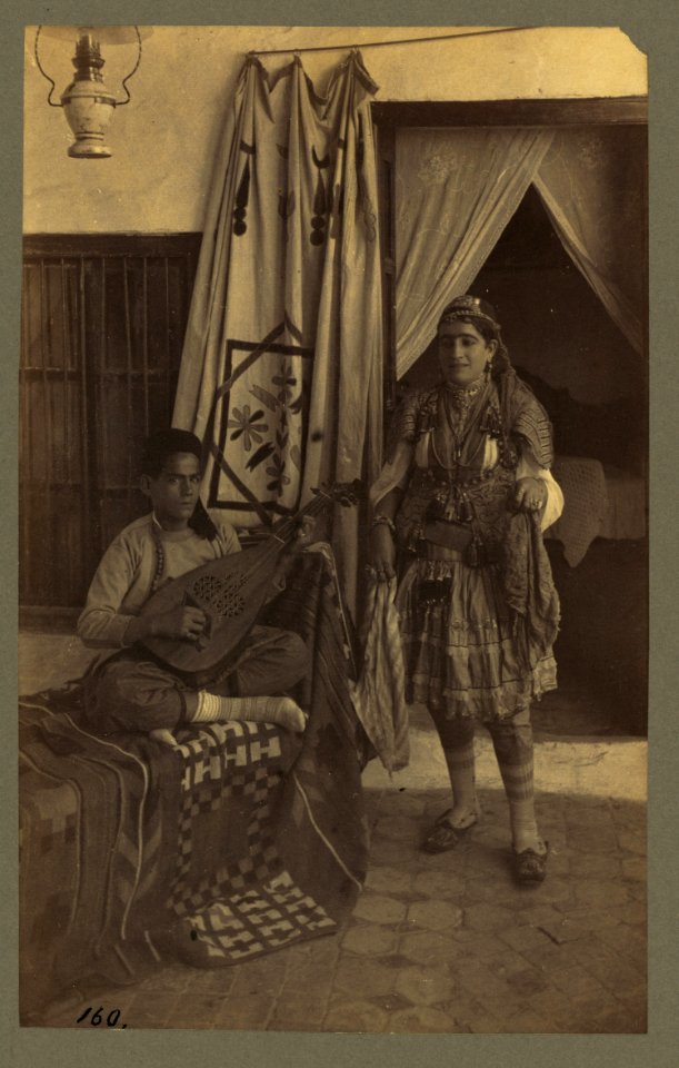 Young man seated, playing an oud, while a young woman stands nearby LCCN2004670407