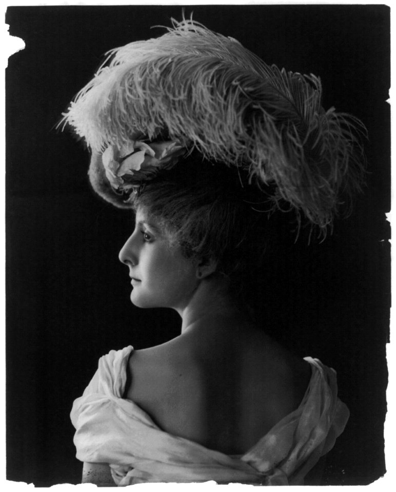 Young woman modeling- back view, head and shoulders, wearing feathered hat LCCN2003677212