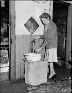 Young wife of a miner drawing water at the tap in her kitchen. This tap was installed by a former tenant, few houses... - NARA - 540942 photo