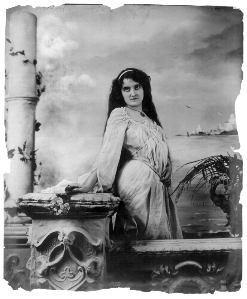 Young woman modeling- 3-4 lgth., standing by wall, in front of body of water LCCN2003677234