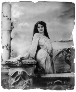Young woman modeling- 3-4 lgth., standing by wall, in front of body of water LCCN2003677234