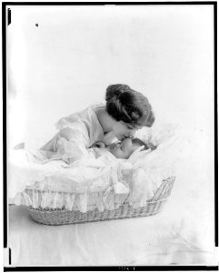 Young woman kissing baby in bassinet LCCN91481582 photo