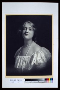 Young woman wearing an off-the-shoulder dress and long pearl necklace, looking front, head-and-shoulders portrait LCCN2004676399 photo