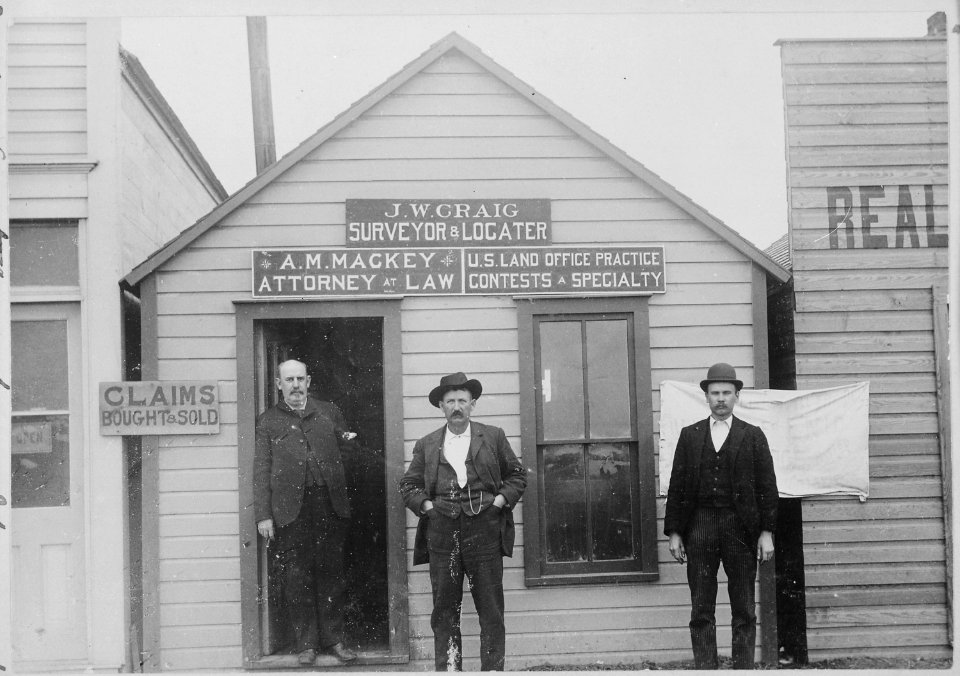 Claims bought and sold. U.S. Land Office practice-contests a specialty. Attorneys and surveyors in front of office, w - NARA - 540091