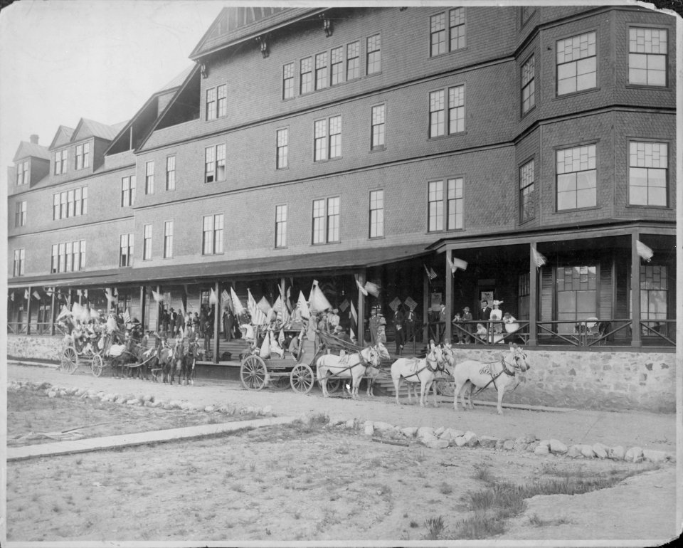 Hot Springs Hotel, S. D. American flags flap in the breeze as holiday passengers arrive. The stage coaches are met by - NARA - 516370