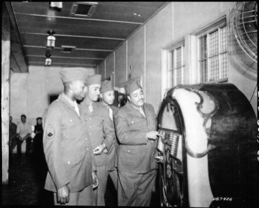First of the famous Mills Brothers quartet to enter Army service, Pvt. Harry Mills stops at the jukebox in the Receptio - NARA - 531178 photo