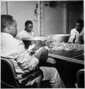 Steward's mates joke as they dry silverware in the wardroom of U.S.S. Ticonderoga (CV-14)., 11-1944 - NARA - 520869