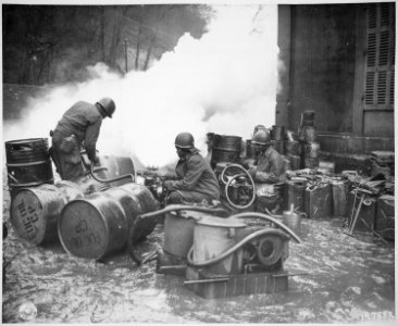 Soldiers of the 161st Chemical Smoke Generating Company, U.S. Third Army, move a barrel of oil in preparation to refill - NARA - 531229 photo