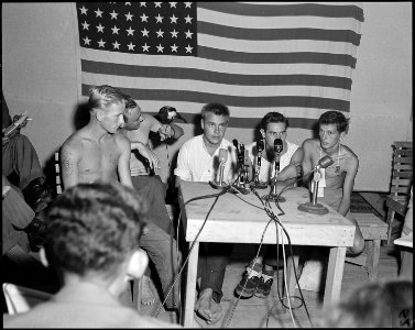 A group of POWs being interviewed by the press at Freedom Village, Korea, proudly display their camp mascot Oscar a... - NARA - 542274 photo