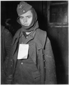 A German prisoner of war captured near Ubach, Germany, wears a tag telling his captors that he has an injured back... - NARA - 531499 photo