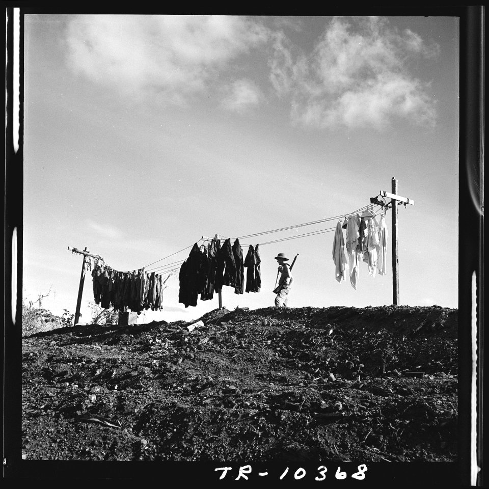 A Marine walking guard duty on Roi Island past a line of clothes drying. - NARA - 520720