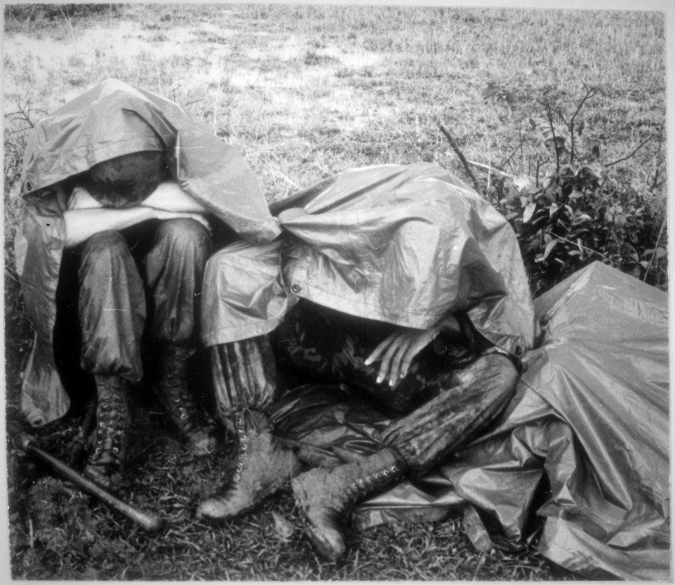 A BREAK IN THE RAIN-Two battle weary Leathernecks of the 26th Marine Regiment take a break, rain and all, during... - NARA - 532462