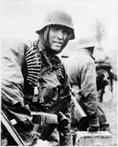 A Nazi soldier, heavily armed, carries ammunition boxes forward with companion in territory taken by their... - NARA - 531230