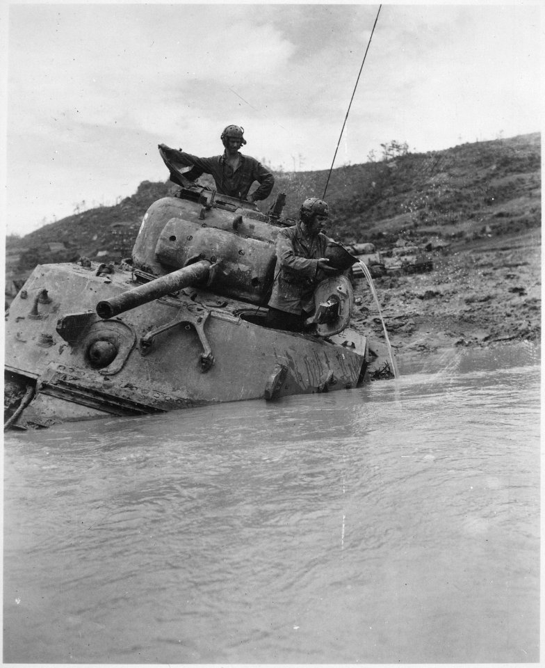 A tank sunk in 5 feet of water waits for towing equipment. The Tank Commander gives vent to his feelings with a... - NARA - 531305