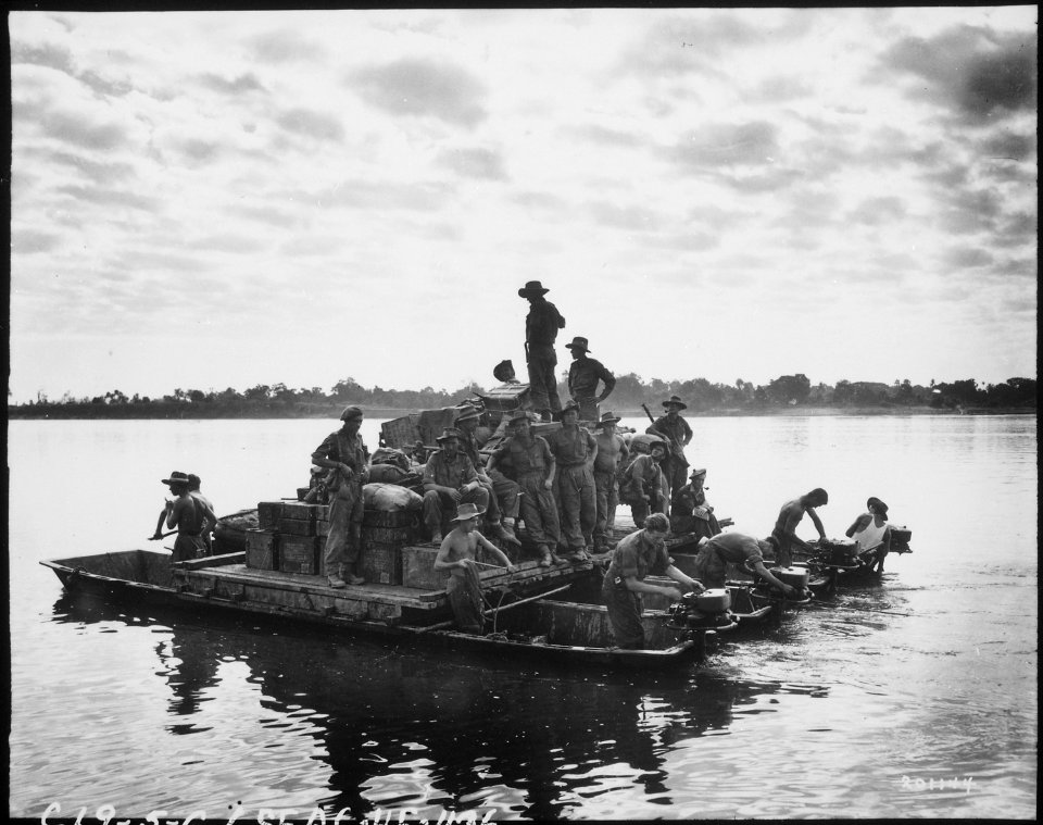 A barge, powered by outboard motors, crosses the Irrawaddy River near Tigyiang, Burma. The men, their truck and... - NARA - 531250