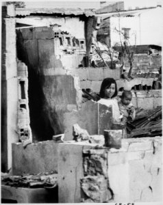 A girl, holding a small child, stands in the ruins of their home after a Viet Cong attack. Saigon, January 31, 1968., 19 - NARA - 541980