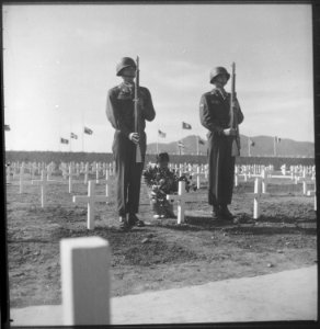 A little Korean girl places a wreath of flowers on the grave of an American soldier, while Private First Class... - NARA - 530634