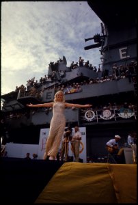 Actress Carol Baker throws open her arms to the men of the aircraft carrier Ticonderoga (CVA-14) as the ship steams... - NARA - 558510