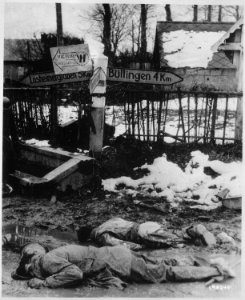 American soldiers, stripped of all equipment, lie dead, face down in the slush of a crossroads somewhere on the... - NARA - 531237 photo