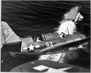 Aerial view of SB2C in upper landing circle showing USS YORKTOWN, below. - NARA - 520696