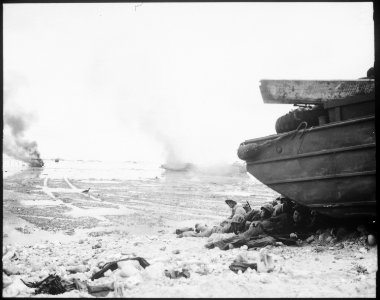 An amphibious tractor burns on the beach as Marines take shelter under a duck. Peleliu, September 1944. - NARA - 532534