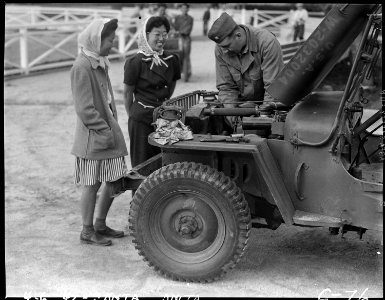 Arcadia, California. Two young evauees of Japanese ancestry watch an army mechanic repair a Jeep . . . - NARA - 537448