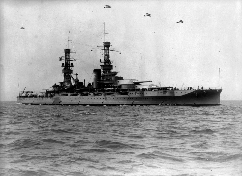 Arizona (BB39). Starboard bow, underway with aircraft overhead retouched