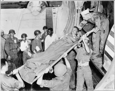 BACK FROM THE FIGHTING FRONT. A group of war-weary wounded soldiers stand by while one of their number is lifted from... - NARA - 542217 photo