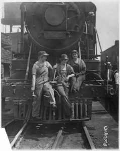 Busch (Bush) Terminal. Women laborers seated on front of engine in railroad yard. War industries picture. - NARA - 522868