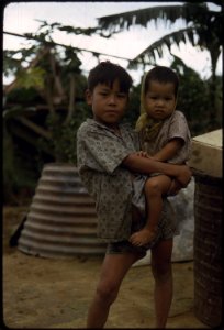 Camp Campbell, Phu Bai, Republic of Vietnam... A Vietnamese boy carries a young child. - NARA - 558514