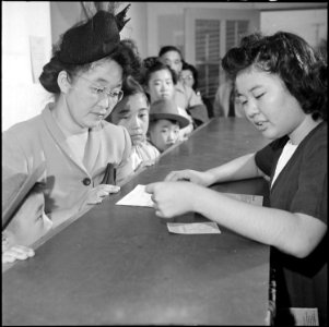 Colorado River Relocation Center, Poston, Arizona. A relocatee receiving a ration book prior to boa . . . - NARA - 539899