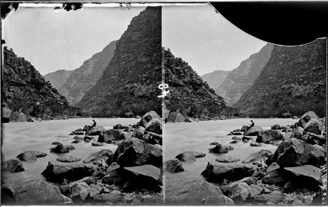Colorado River. Cataract Canyon, Clem Powell reading while sitting on a boulder in the river. See - NARA - 517890