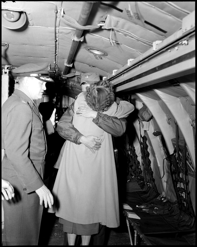 COMBAT CARGO, JAPAN-Clasping his wife tightly in his arms, aboard a Combat Cargo C-124 Globemaster just after it... - NARA - 542286