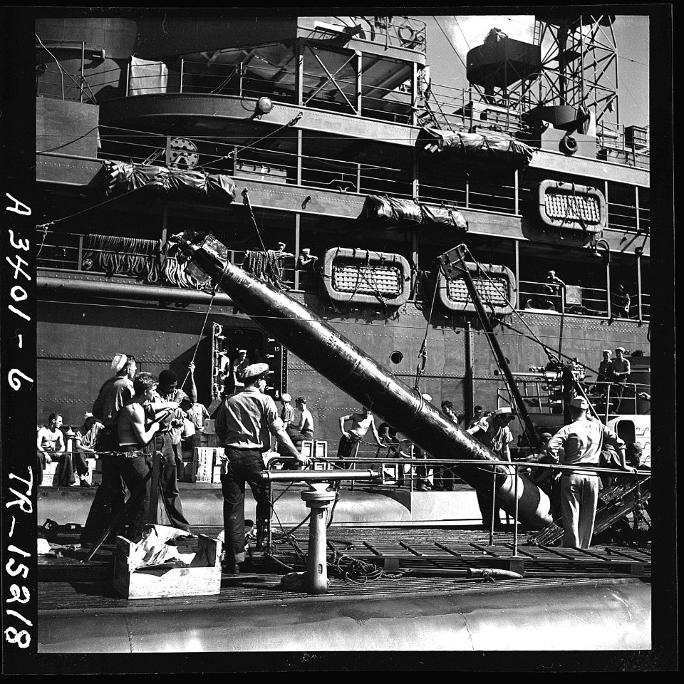 Crewmen transferring a torpedo from a submarine tender to a submarine about to leave on war patrol. - NARA - 520831