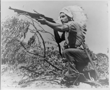 Dan Waupoose, a Menomini chief, full-length, kneeling with a rifle and wearing a feathered headdress, Algiers, Lousiana, - NARA - 520636