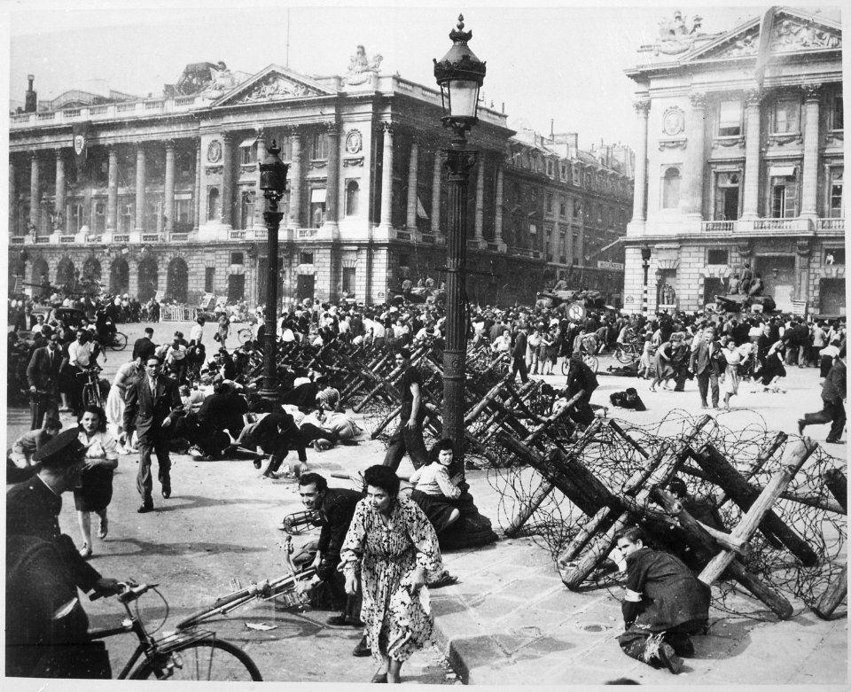 Crowds of Parisians celebrating the entry of Allied troops into Paris scatter for cover as a sniper fires from a... - NARA - 531206