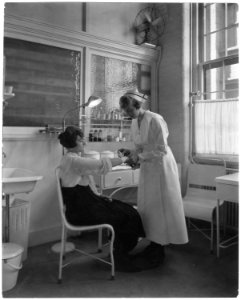 Eastman Kodak Company. Rendering first aid. Woman's arm being bandaged by nurse. - NARA - 522862
