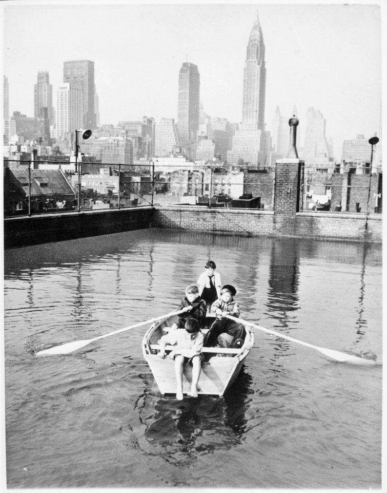 Four young members of the Madison Square Boy's Club rowing a boat in a rooftop pool, Manhattan skyscrapers in the backgr - NARA - 541907