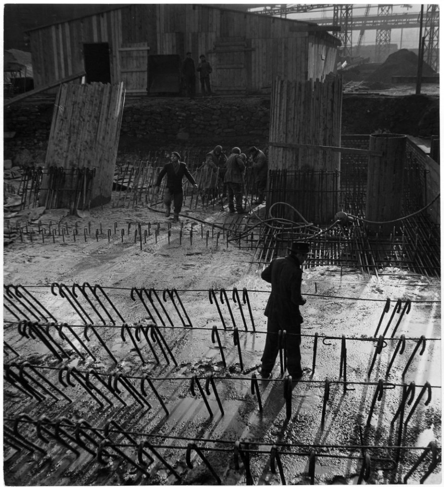 France. Standing in a bog of cement, laborer wiring on the stiffeners. Workers in background have received load of... - NARA - 541671