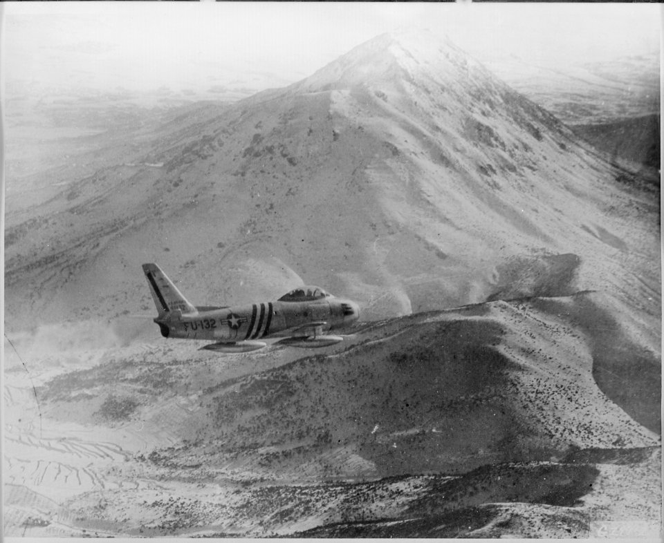 Framed against a rugged, snow covered mountain peak in North Korea, a 5th Air Force F-86 Sabre, of the 4th Fighter ... - NARA - 542218