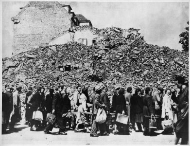Germany. (A line of people with baggage in front of a pile of building rubble.) - NARA - 541694