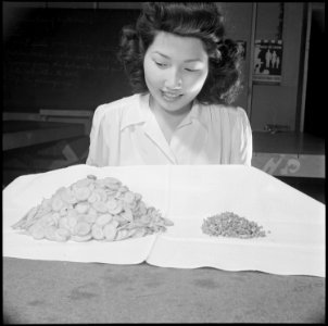 Gila River Relocation Center, Rivers, Arizona. Mary Sakai demonstrating the loss in volume of veget . . . - NARA - 537063 photo