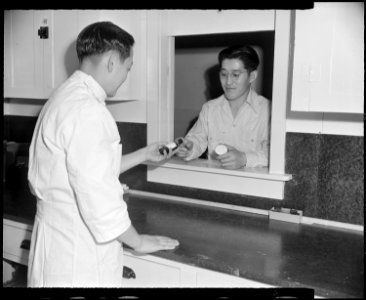 Granada Relocation Center, Amache, Colorado. A resident of the center receives a prepared prescript . . . - NARA - 539050