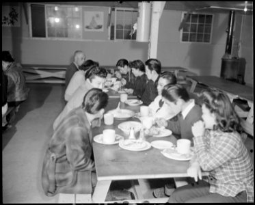 Granada Relocation Center, Amache, Colorado. A group of residents loll over their evening meal. - NARA - 539054